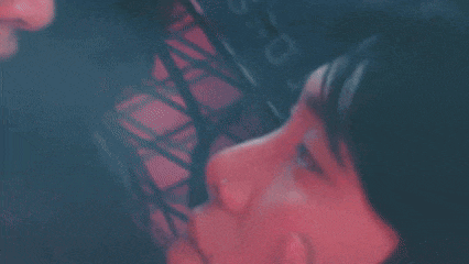 a close up of a person 's face in a dark room with a red background .