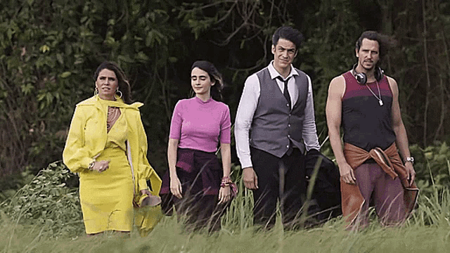 a group of people standing in a grassy field including a man wearing headphones