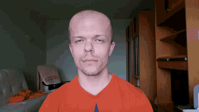 a bald man with a beard wears an orange shirt with the word converse on it
