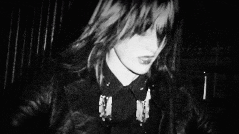 a black and white photo of a woman with her eyes closed and a jacket on .