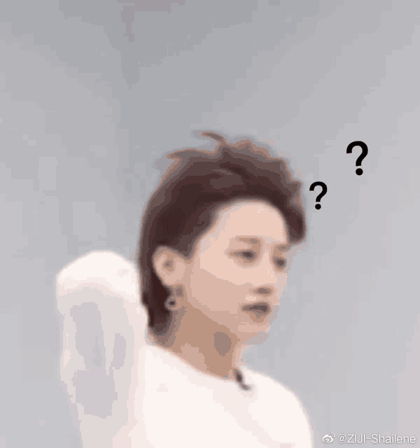 a close up of a person 's face with three question marks floating around their head .