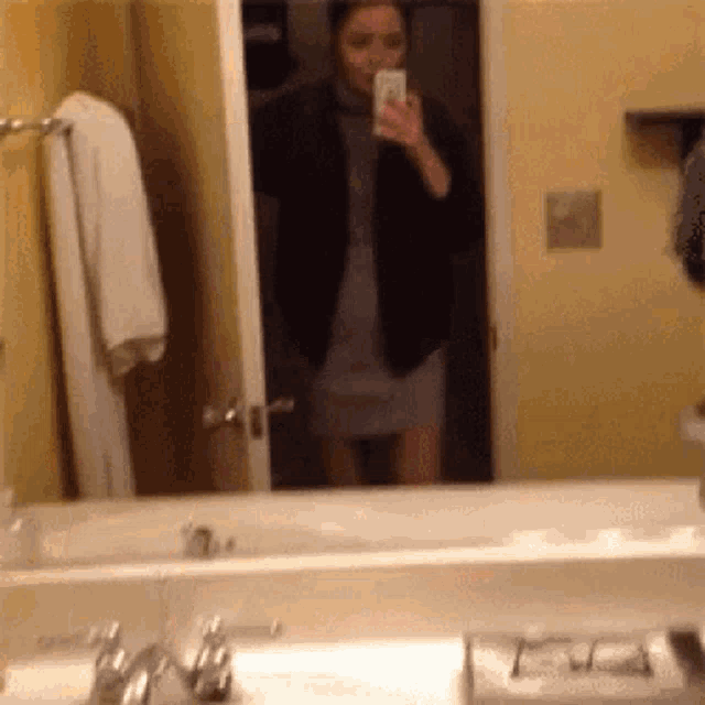 a woman is taking a picture of herself in the bathroom mirror