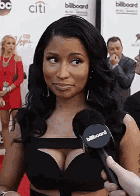a woman in a black dress is being interviewed by a microphone .