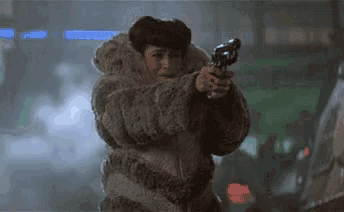 a woman in a fur coat is pointing a gun at someone .