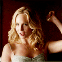 a woman with blonde hair is flexing her muscles in front of a red wall