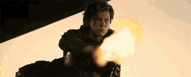 a woman is pointing a gun at the camera