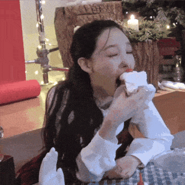 a woman is eating a piece of cake with a candle in the background .
