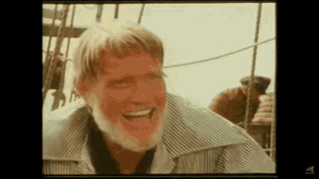 a man with a beard and a striped shirt is smiling .