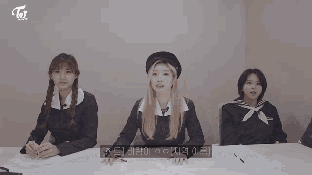 three girls are sitting at a table with the word twice on the bottom right