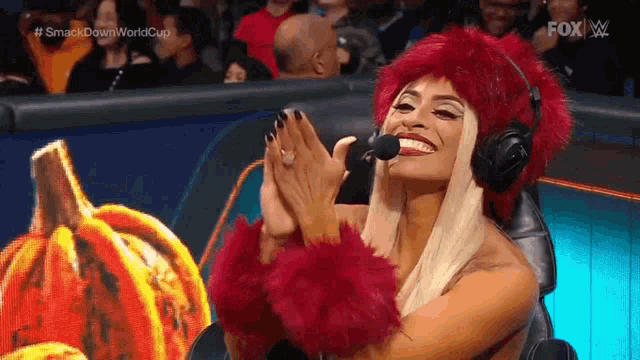 a woman wearing a red fur hat and headphones is clapping her hands .