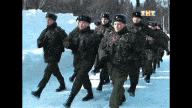 a group of soldiers marching in the snow with the letters tht on the bottom right