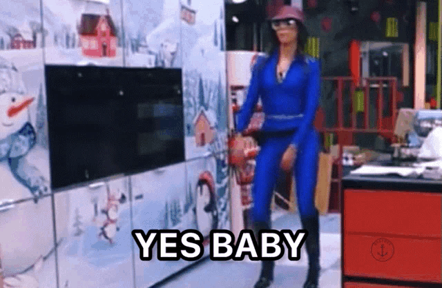 a woman in a blue jumpsuit says yes baby in a kitchen