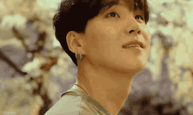 a close up of a young man wearing earrings and looking up .