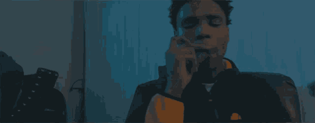 a man is smoking a cigarette in a dark room with a blue light behind him .