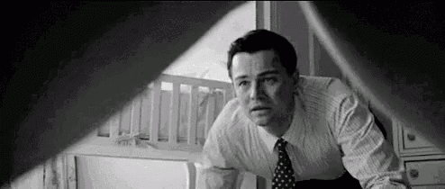 a man in a suit and tie is looking out a window at a baby crib .