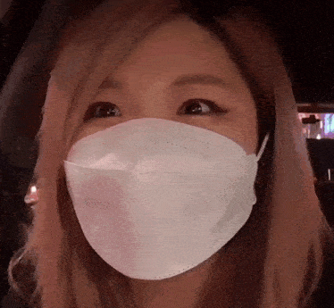 a woman with pink hair wearing a white face mask