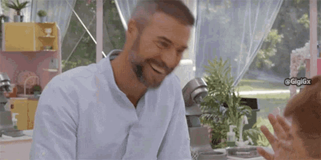 a man with a beard and a white shirt is smiling in a kitchen .