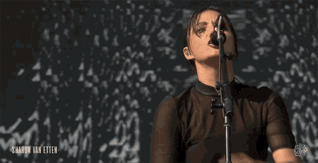 a woman singing into a microphone with sharon van etten written on the bottom right