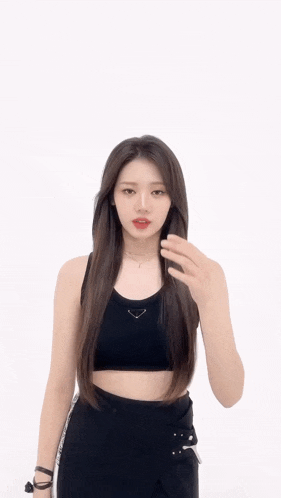 a woman in a black crop top and black pants giving the peace sign