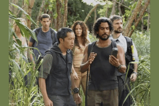 a group of people are walking through a lush green forest and one of them is holding a cell phone