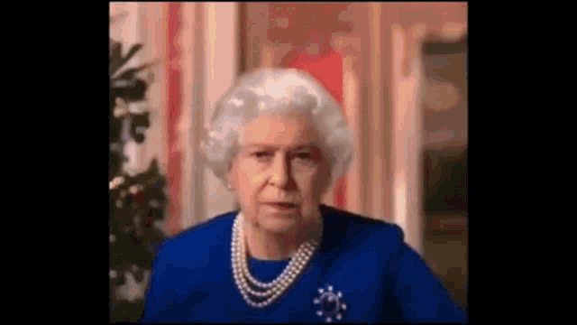 queen elizabeth ii is wearing a blue dress and pearls while giving a speech .