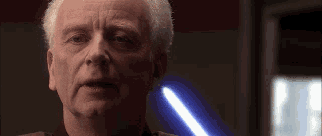 a close up of a man 's face with a blue light in the background