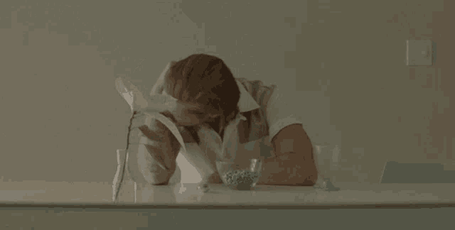 a woman sits at a table with her head down