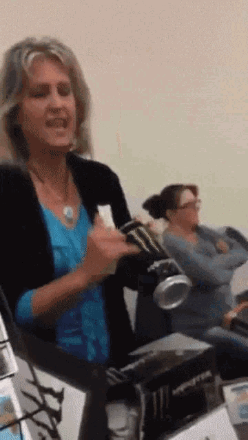 a woman in a blue shirt is holding a monster can