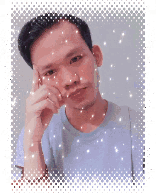 a man in a blue shirt is looking at the camera with snow falling on his face