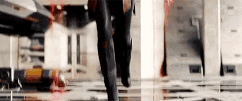 a man in a suit is walking through a room with a red light behind him .