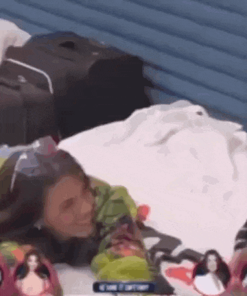 a woman is laying on a bed with a suitcase and a doll .