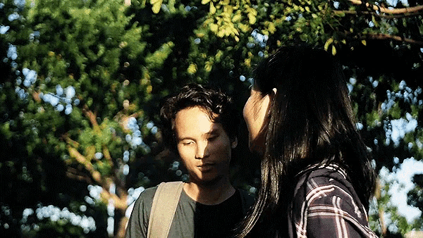 a man and a woman are standing under a tree and looking at each other
