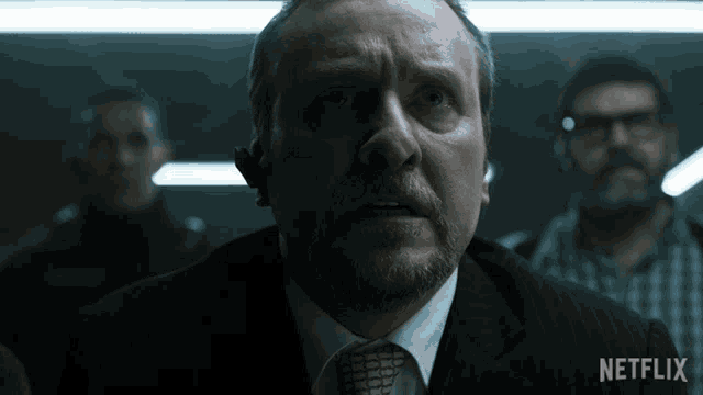 a man in a suit and tie with a netflix logo on the bottom right