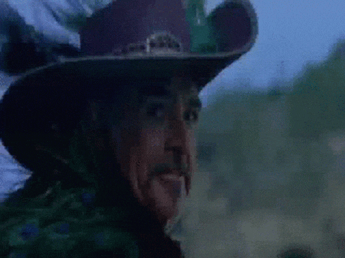 a close up of a man wearing a cowboy hat looking at the camera