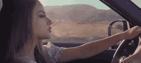 a woman is sitting in a car with her eyes closed