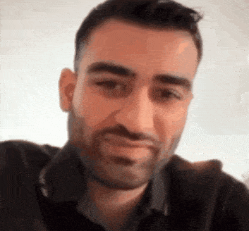 a man with a beard is smiling for the camera .