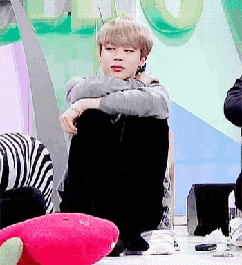 a young man is sitting on the floor with his arms around his knee