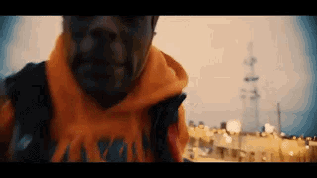 a man wearing a scarf and a hoodie is standing in front of a city .