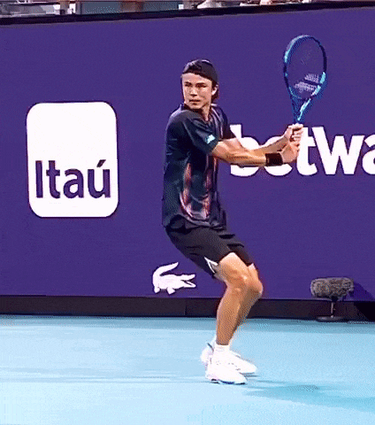 a man is holding a tennis racquet in front of a sign that says itau on it