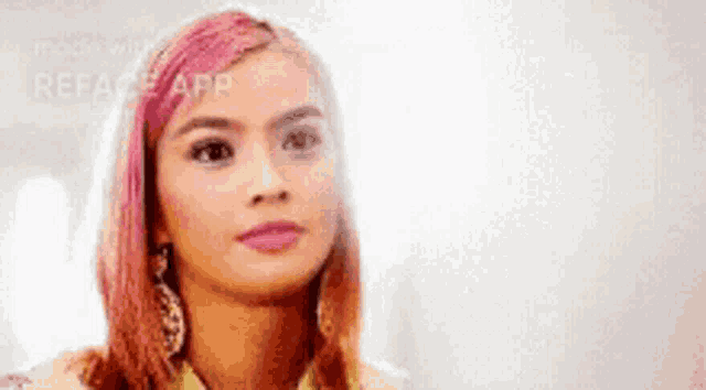 a woman with pink hair is wearing earrings and a jacket .