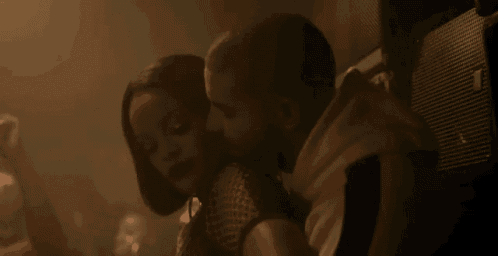 a man and woman are kissing in a dark room .