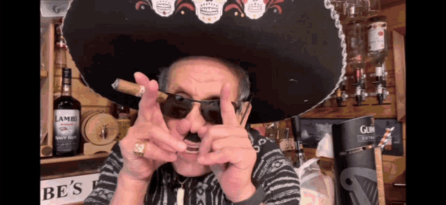 a man wearing a sombrero and sunglasses holds a cigar