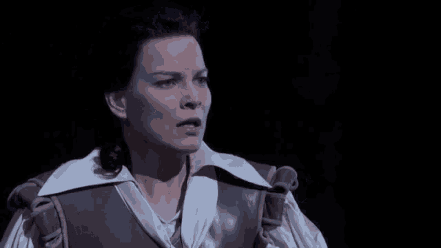 a woman in a brown vest and white collared shirt