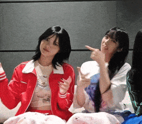 a girl in a red jacket is sitting next to another girl