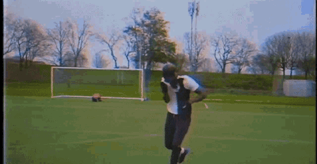 a person is running on a soccer field with a goal in the background .