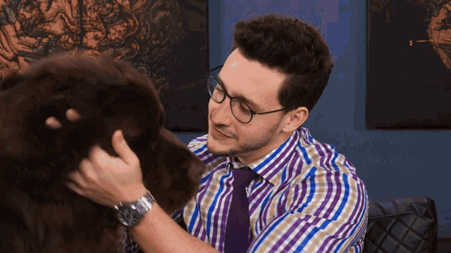 a man in a plaid shirt and tie petting a dog