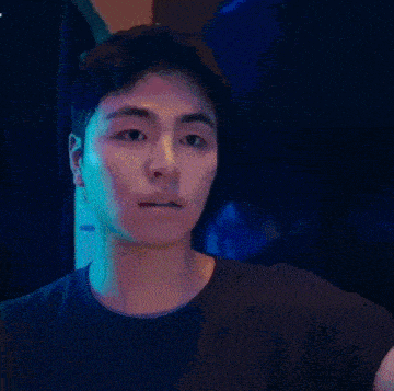 a man in a blue shirt is standing in front of a blue light .