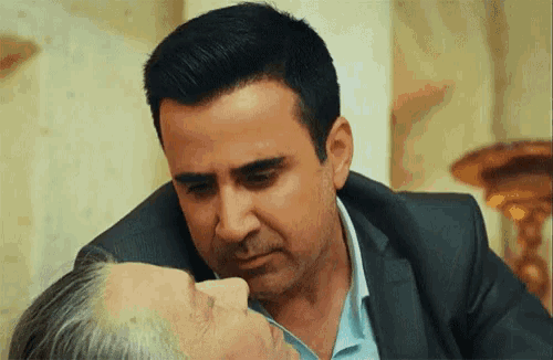 a man in a suit is kissing an older woman on the forehead