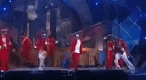 a group of people are dancing on a stage in front of a blue background .