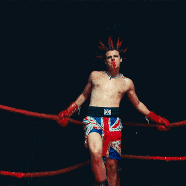 a man wearing boxing shorts with the british flag on them is kicking in a boxing ring